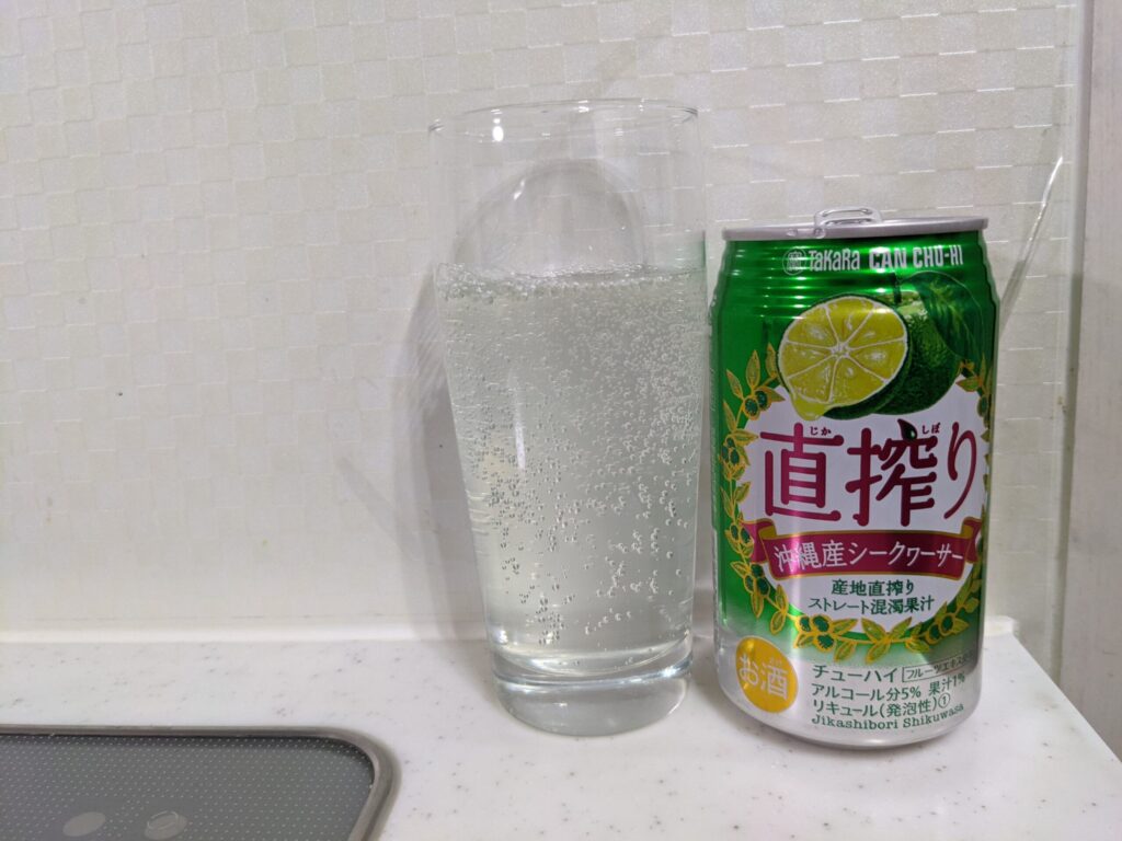 「直搾り沖縄産シークヮーサー」が注がれたグラスとその空き缶
