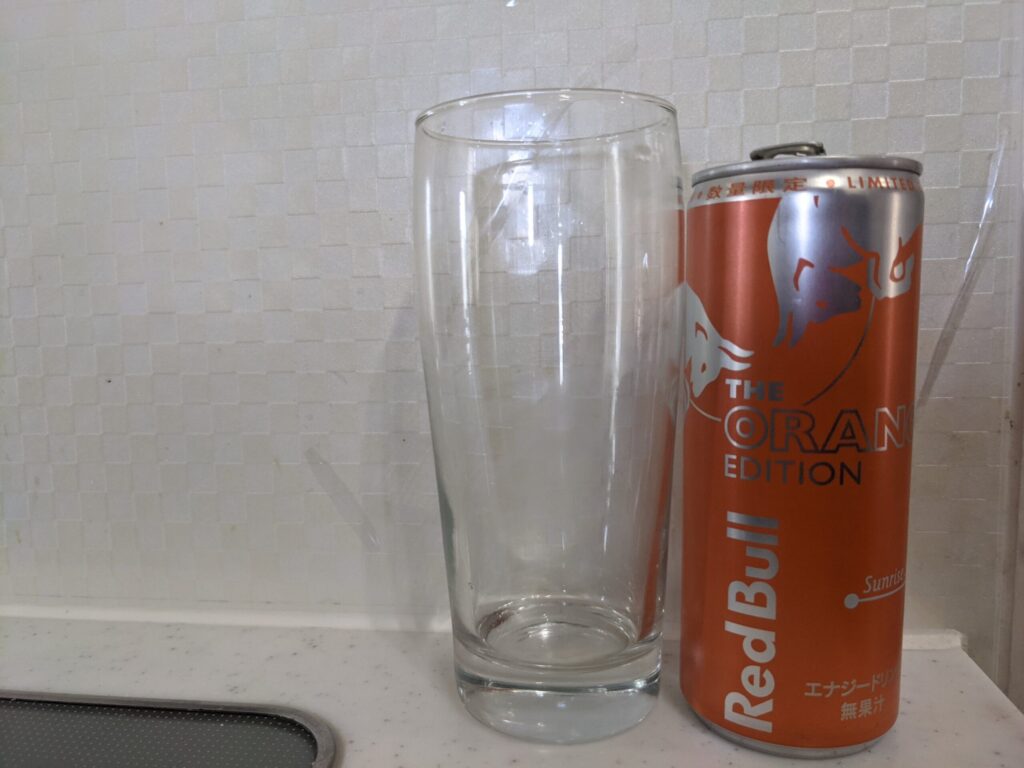 「レッドブルオレンジエディション」が飲み終えたグラスとその空き缶
