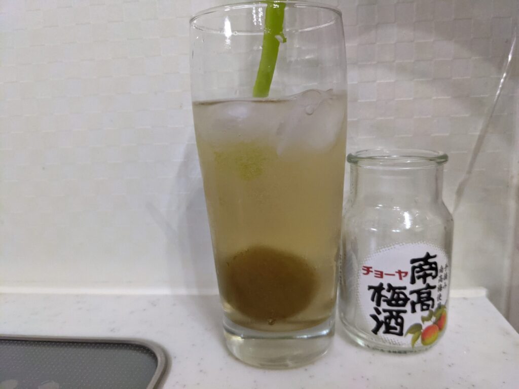 「チョーヤ南高梅酒（梅入り）95mlの炭酸水割り」が入ったグラス内をスプーンで何回もかき混ぜている