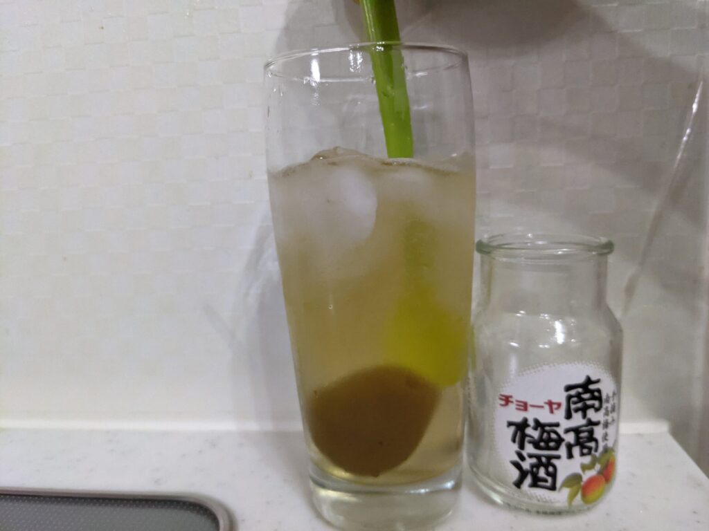 「チョーヤ南高梅酒（梅入り）95mlの炭酸水割り」が入ったグラス内をスプーン継続的に回しているところ