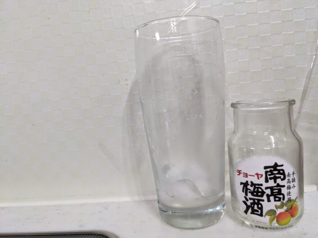 「チョーヤ南高梅酒（梅入り）95mlの炭酸水割り」を飲み終えたグラスとその空き瓶